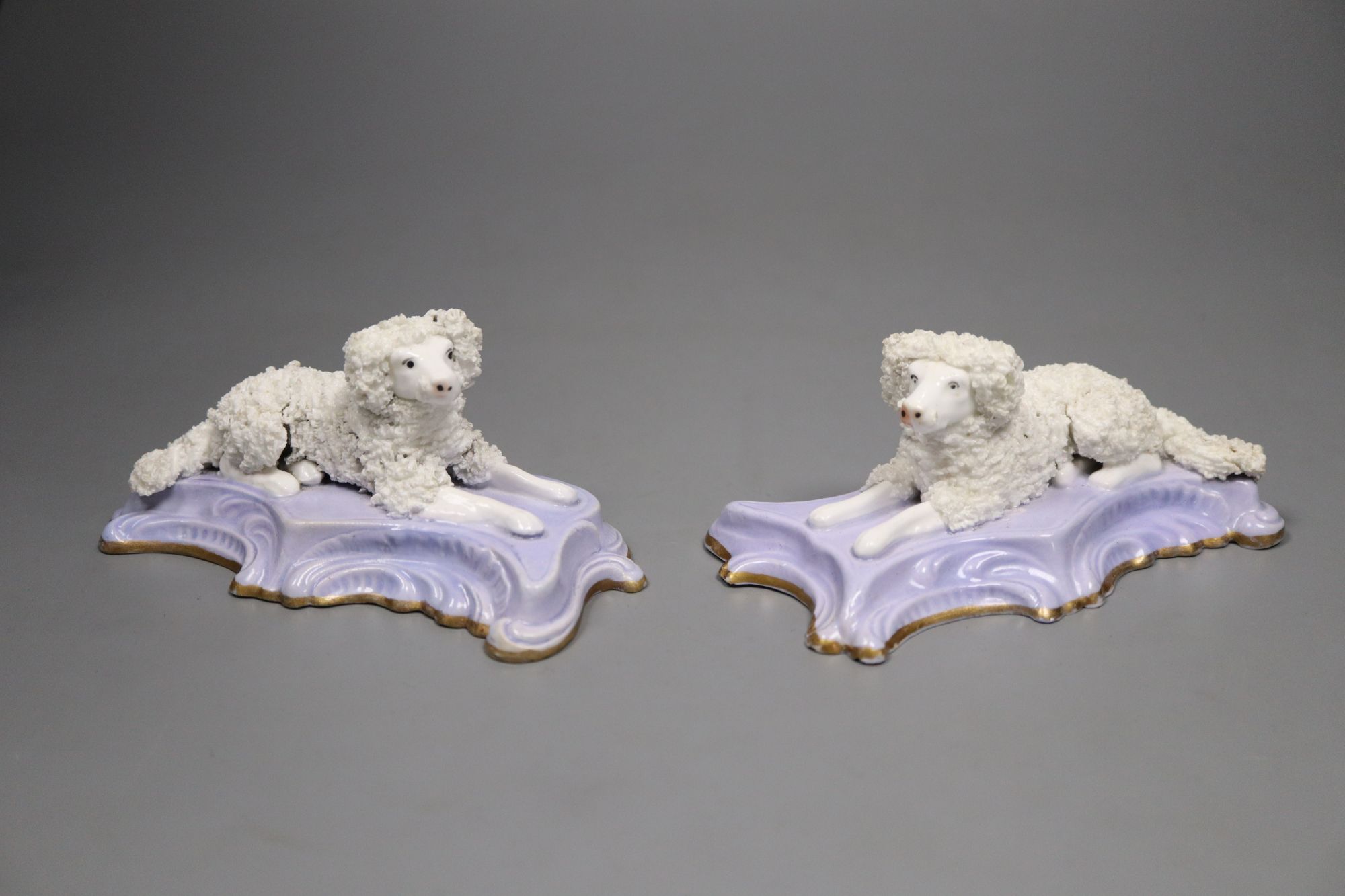 A good pair of Staffordshire porcelain figures of recumbent poodles, c.1835-50, 12.2cm long, lavender ground scrolled bases